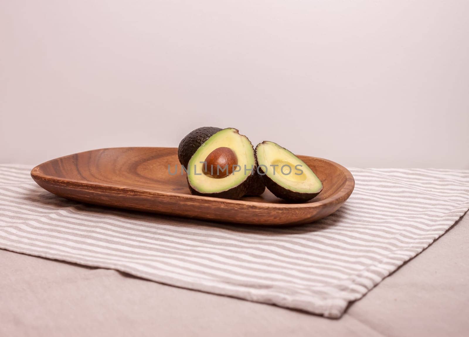 closeup cut avocado on wooden plate at table