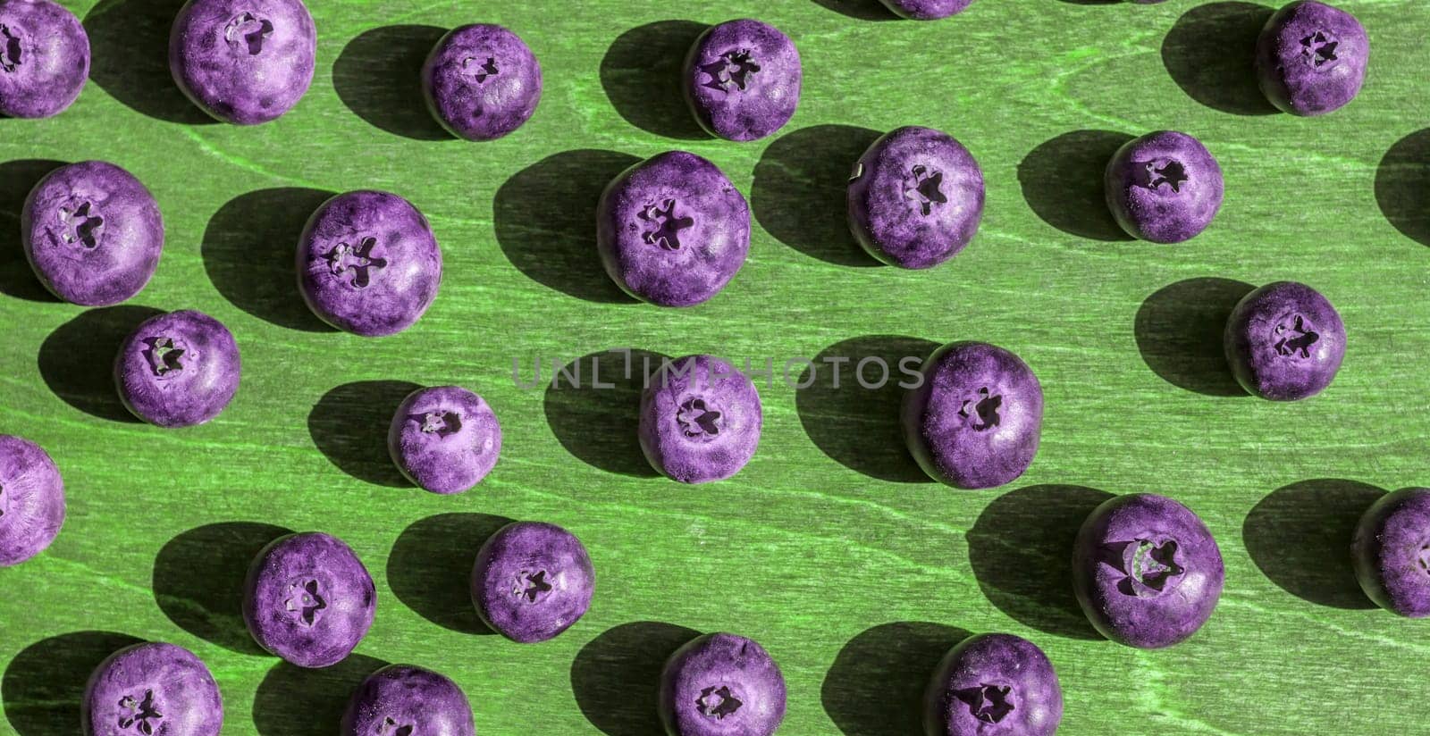 big violet toned blueberries wooden green background bright shadows