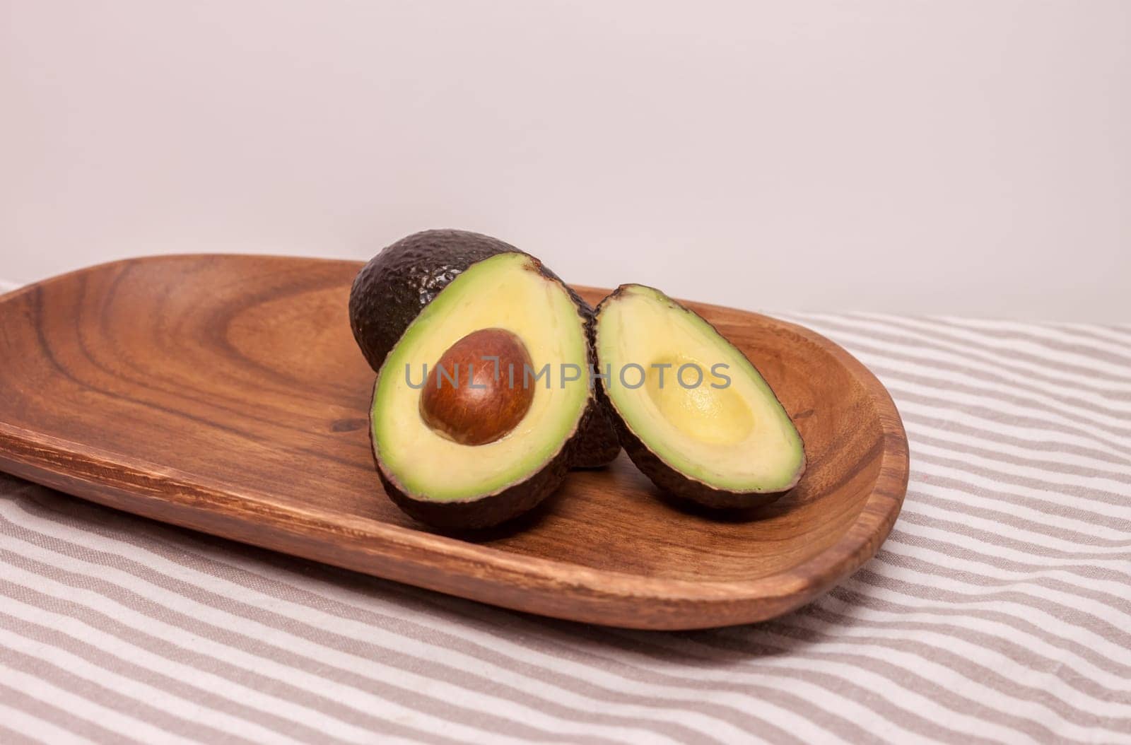 closeup cut avocado on wooden plate at table