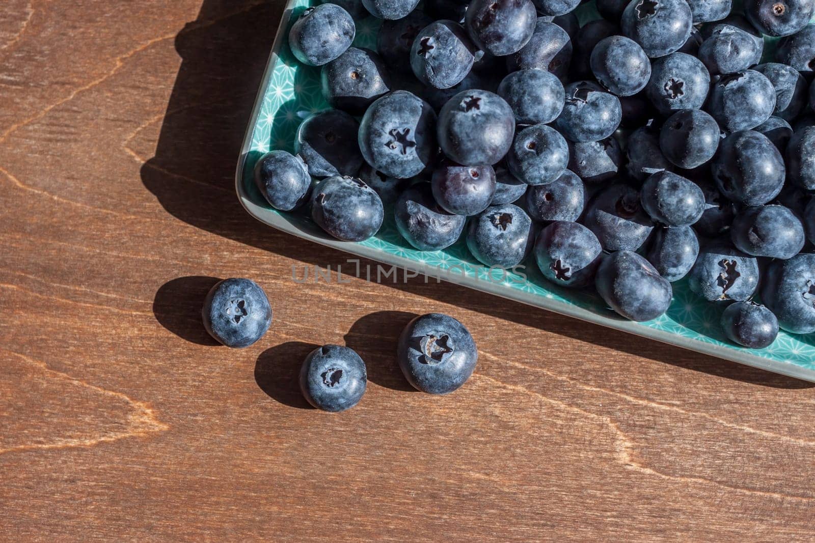 fresh big delicious blueberries in rectangular green plate wooden background