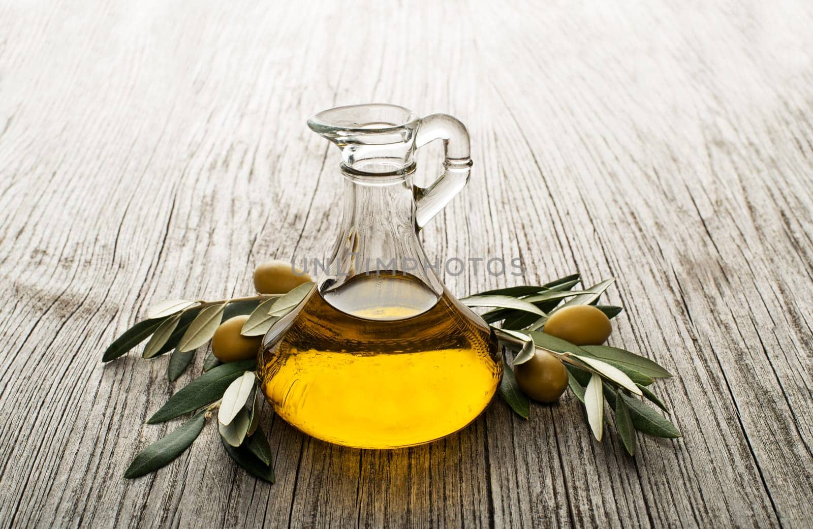 Olive oil with branch on the wooden background