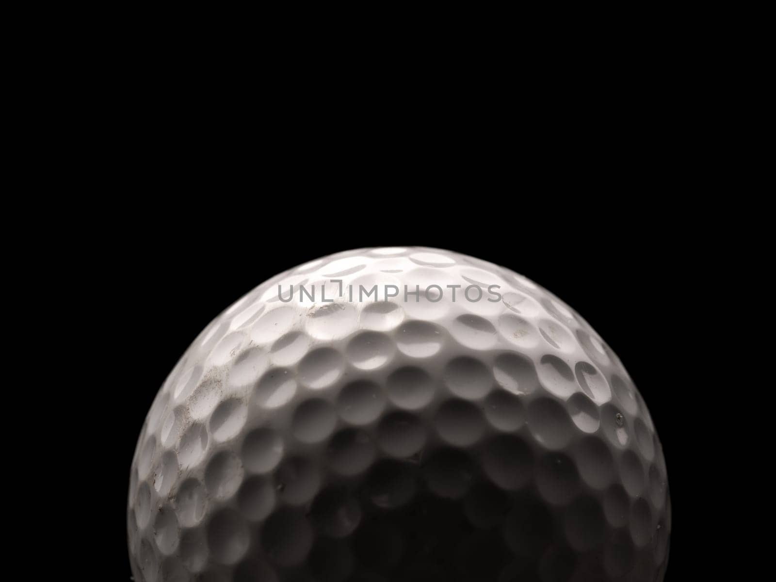 Close up of a used golf ball on a dark background