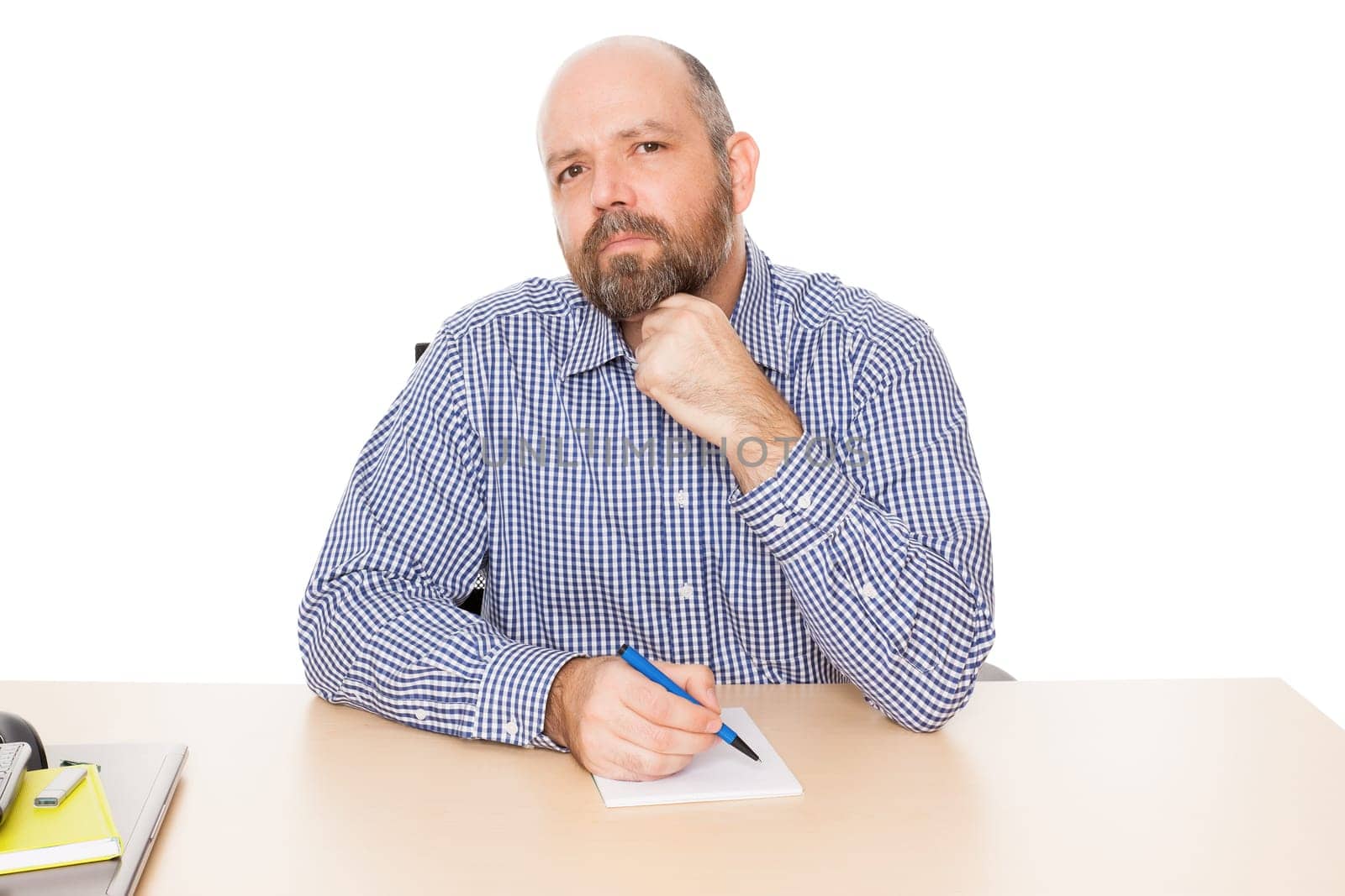 A thoughtful man with a beard at his desk against a white background