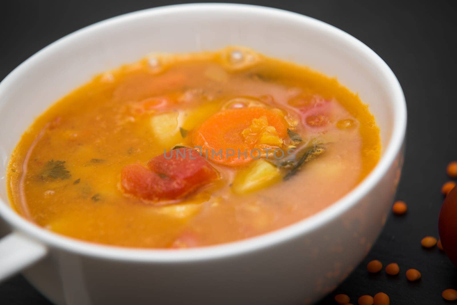 close up on soup with tomato,lentil and potato,rustical background,top view