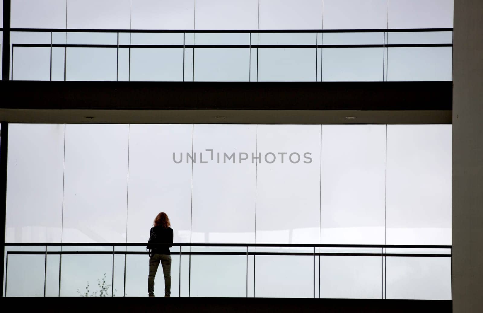 Silhouette view of young businesswoman in a modern office building interior with panoramic windows.