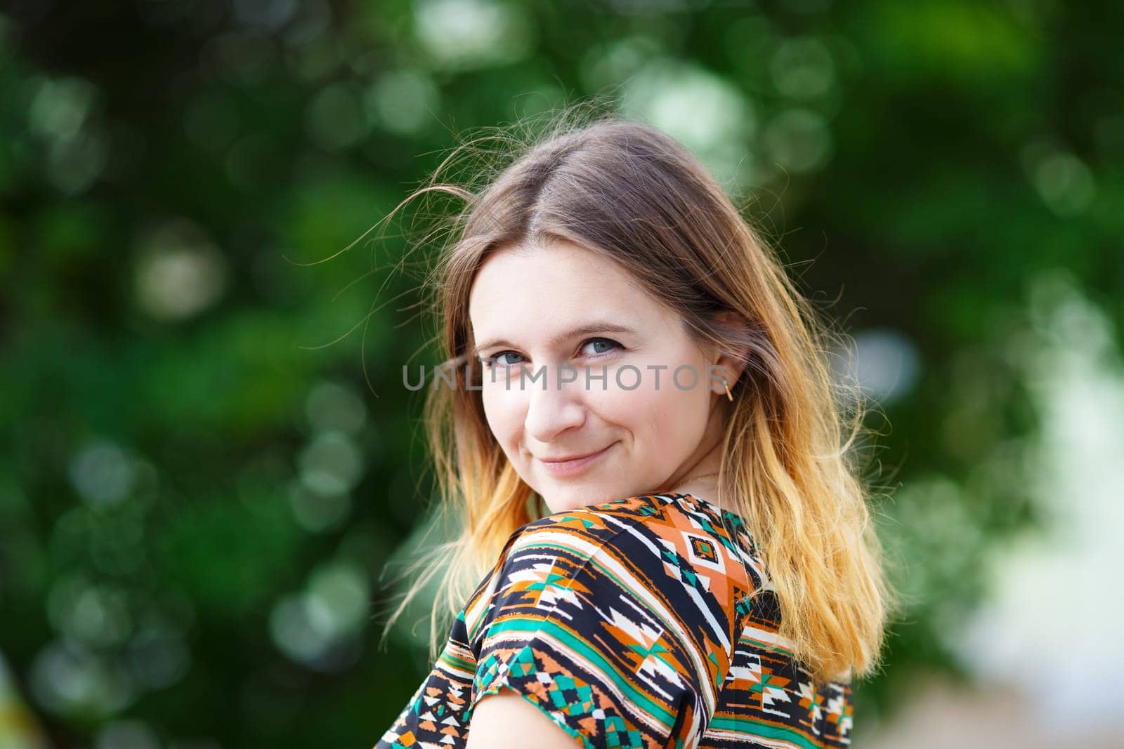 Smiling woman portrait on the blurred green foliage background. Selective focus.