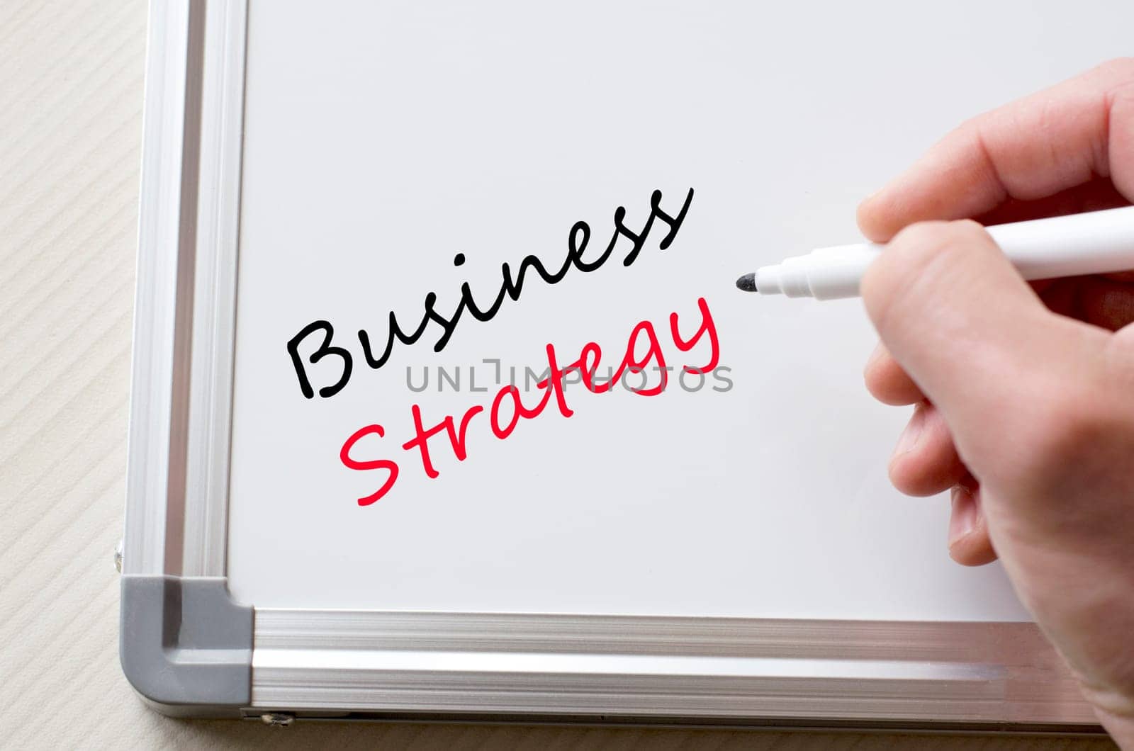 Human hand writing business strategy on whiteboard