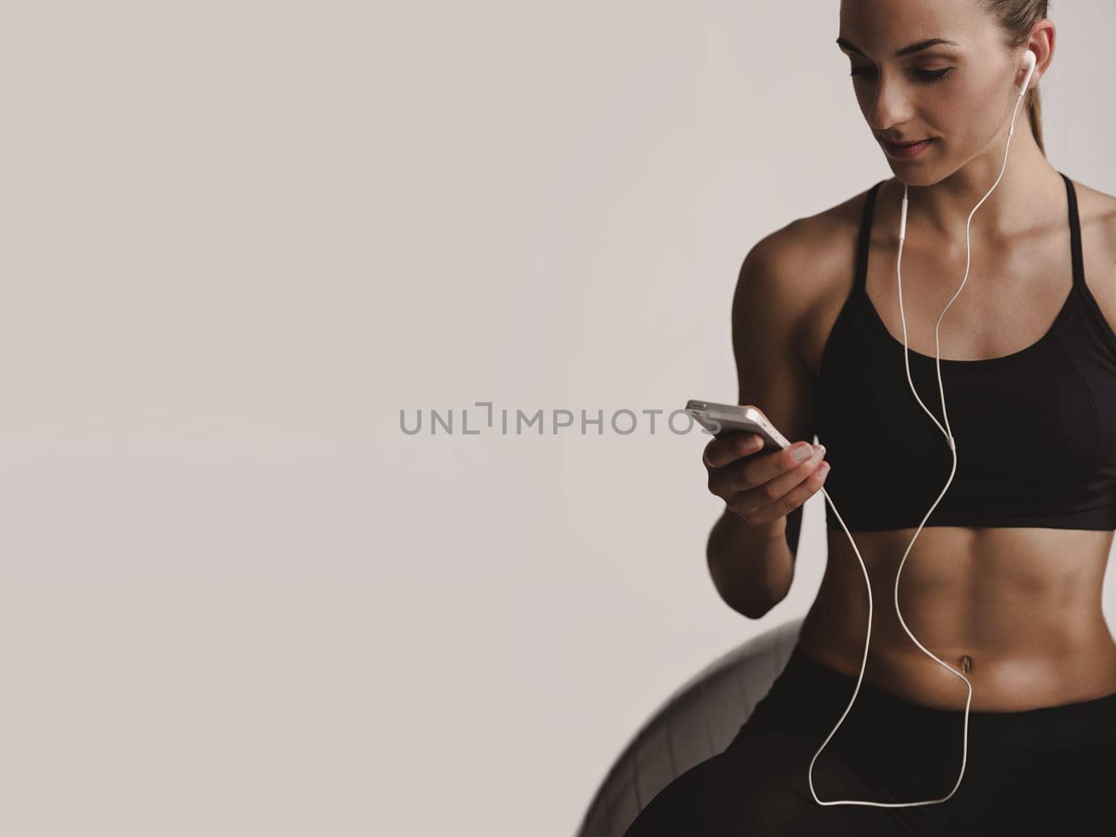 Shot of a beautiful young woman setting the music playlist for the workout.