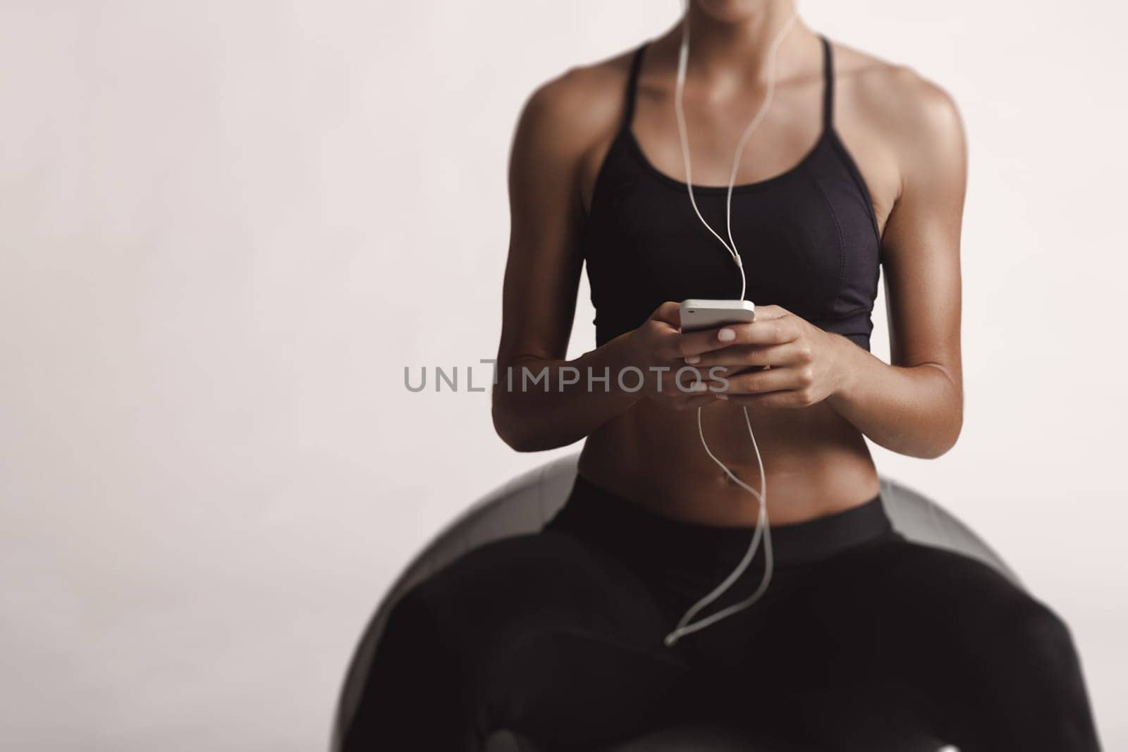 Shot of a beautiful young woman setting the music playlist for the workout.