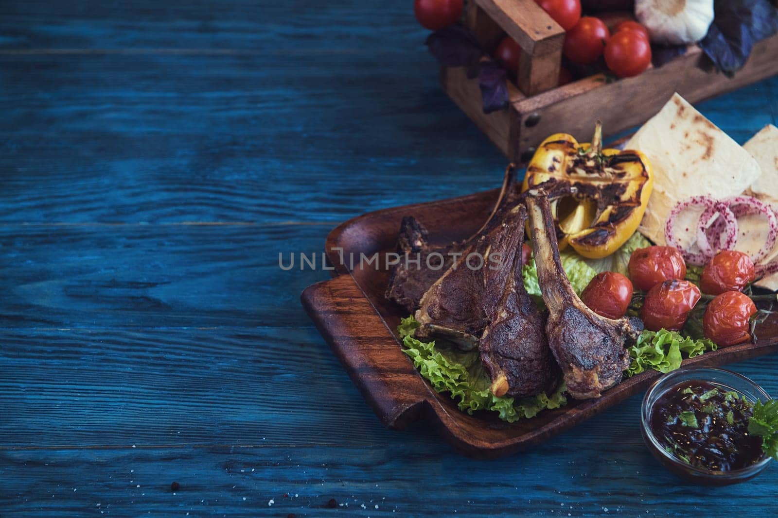 Grilled lamb meat with vegetable on a blue wooden background