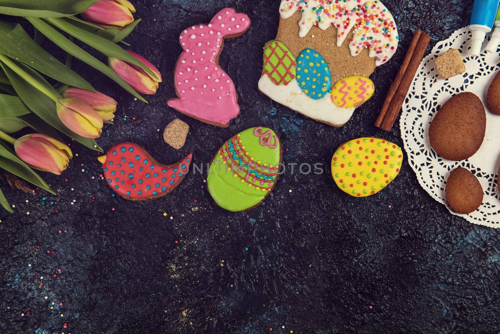 Tulips and gingerbread cookies on darken concrete background for Easter.