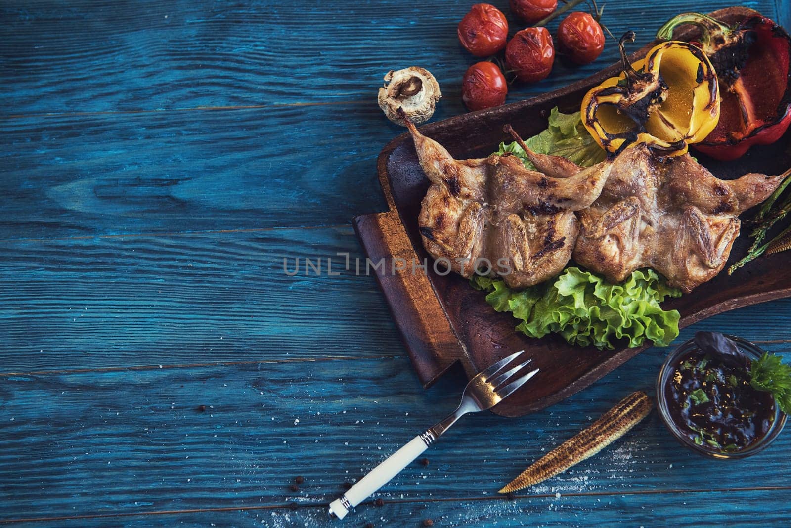 Grilled quail meat with vegetable on a blue wooden background