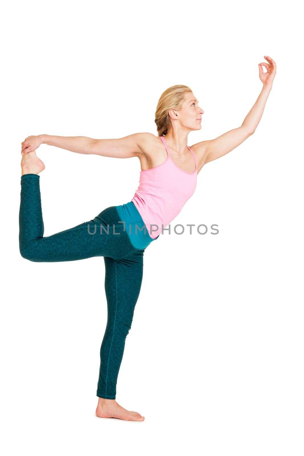 Lateral full-body view of a young woman during yoga exercise "the dancer"" (Natarajasana) against a white background with a slight shadow."