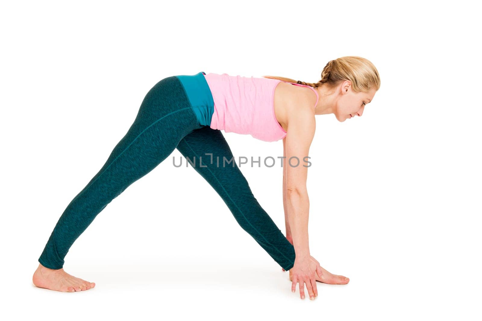 Lateral full-body view of a young woman against a white background showing a variation of the yoga exercise triangle (Triconasana).