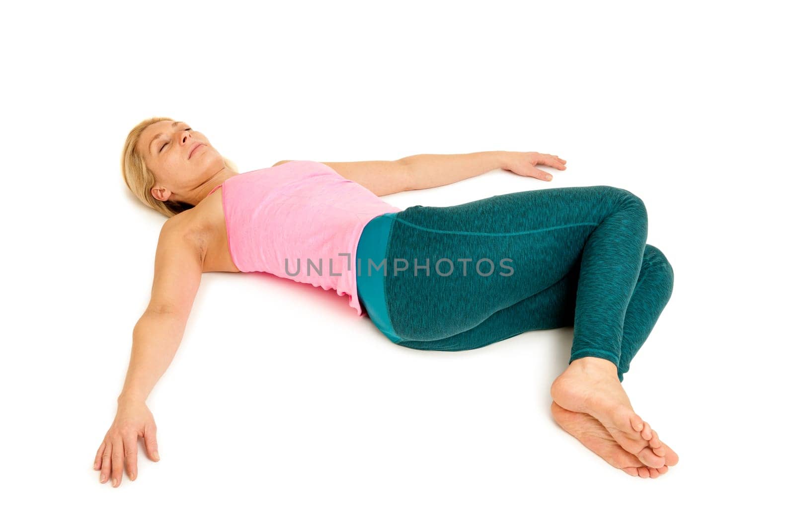 Lateral full-body view of a young woman lying on the floor in the yoga position "Crocodile"" (Nakrasana) on a white background with arms stretched out to the side."