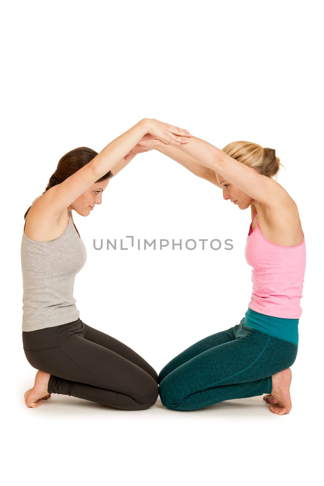 Full body view of two young women in sports dress depicting the letter O on a white background.
