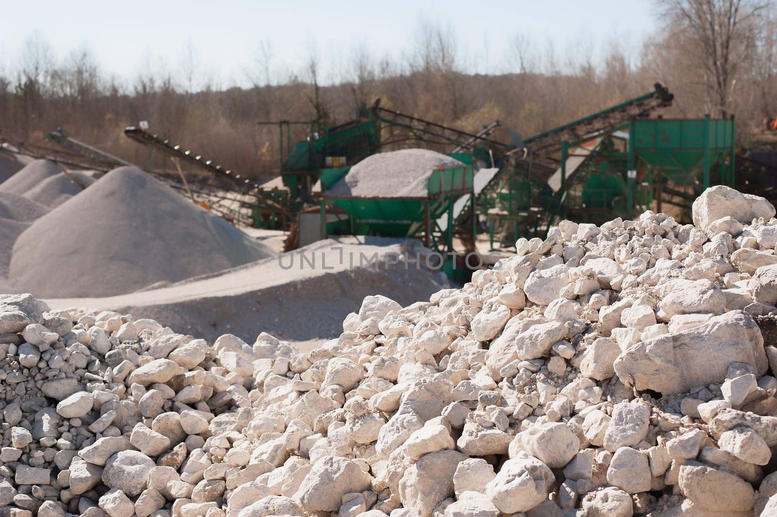 Pile of gravel-rock to be treated. Blurred on background machinery of a gravel pit.