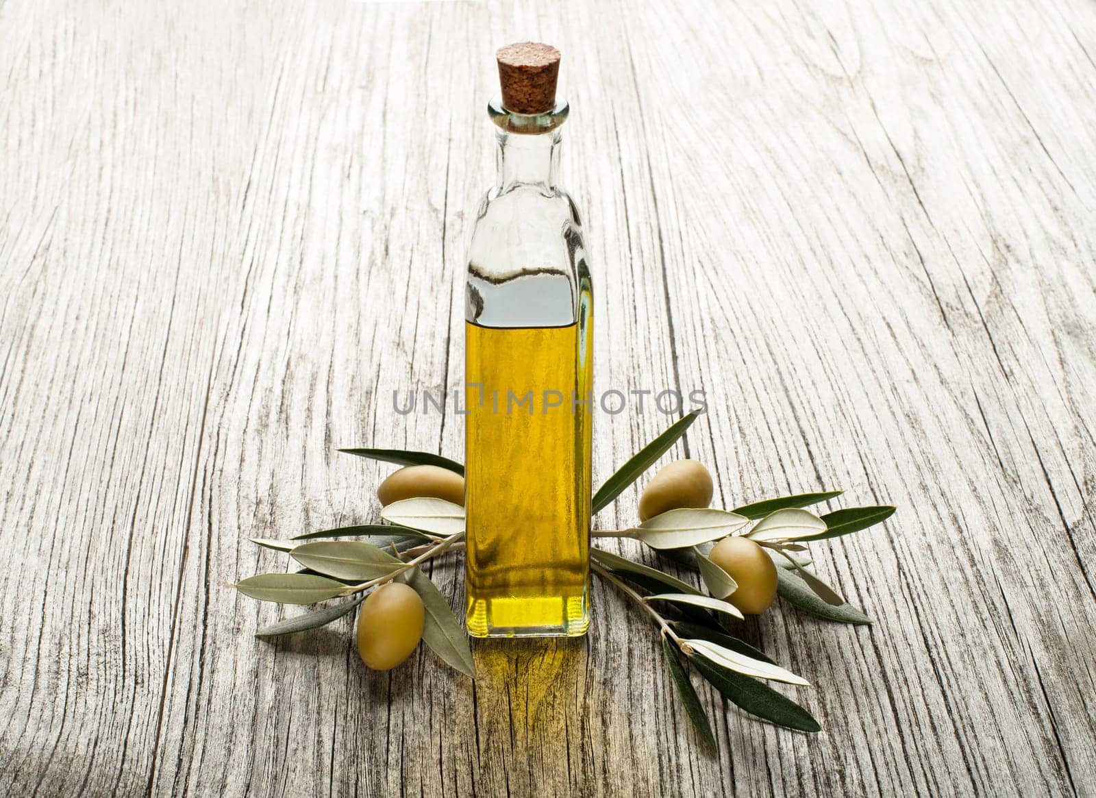Olive oil and olive branch on the wooden table