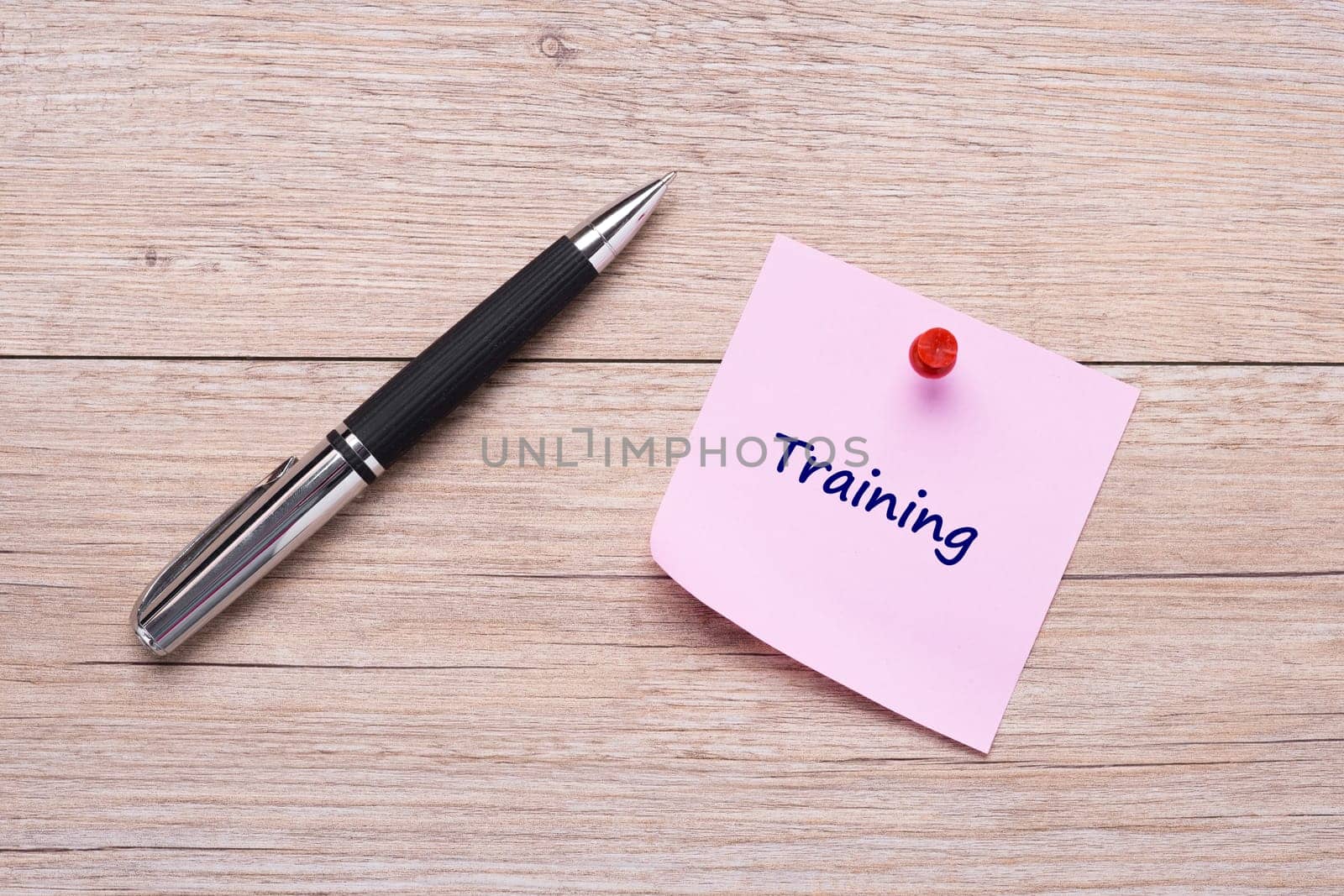 Word training on pink sticky note with red pin and ballpoint pen