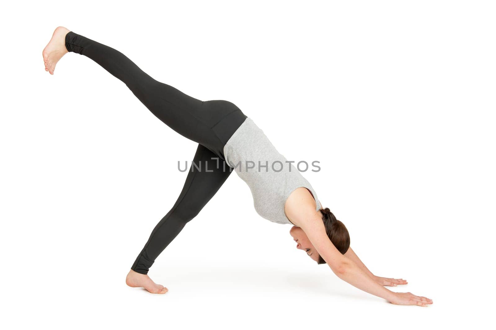 Full-body view of a young black-haired woman on a white background in a variant of the yoga position looking down dog (adho muka shavasana).
