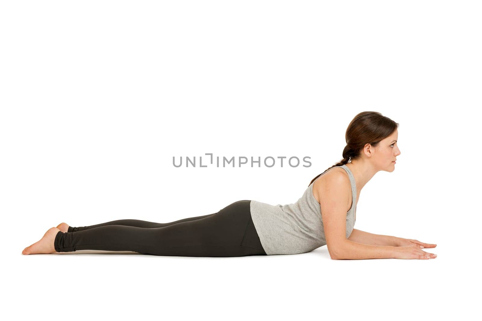Lateral full-body view of a young woman white background showing the yoga position the Sphinx (Salamba Bhujangasana) in the basic position.