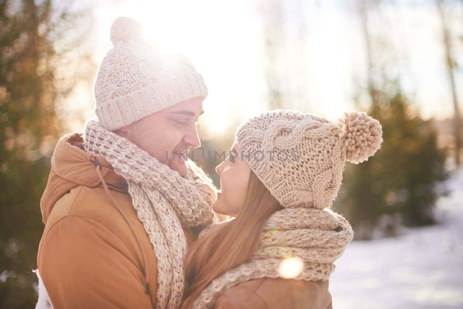 Young amorous couple in winterwear looking at one another outdoors