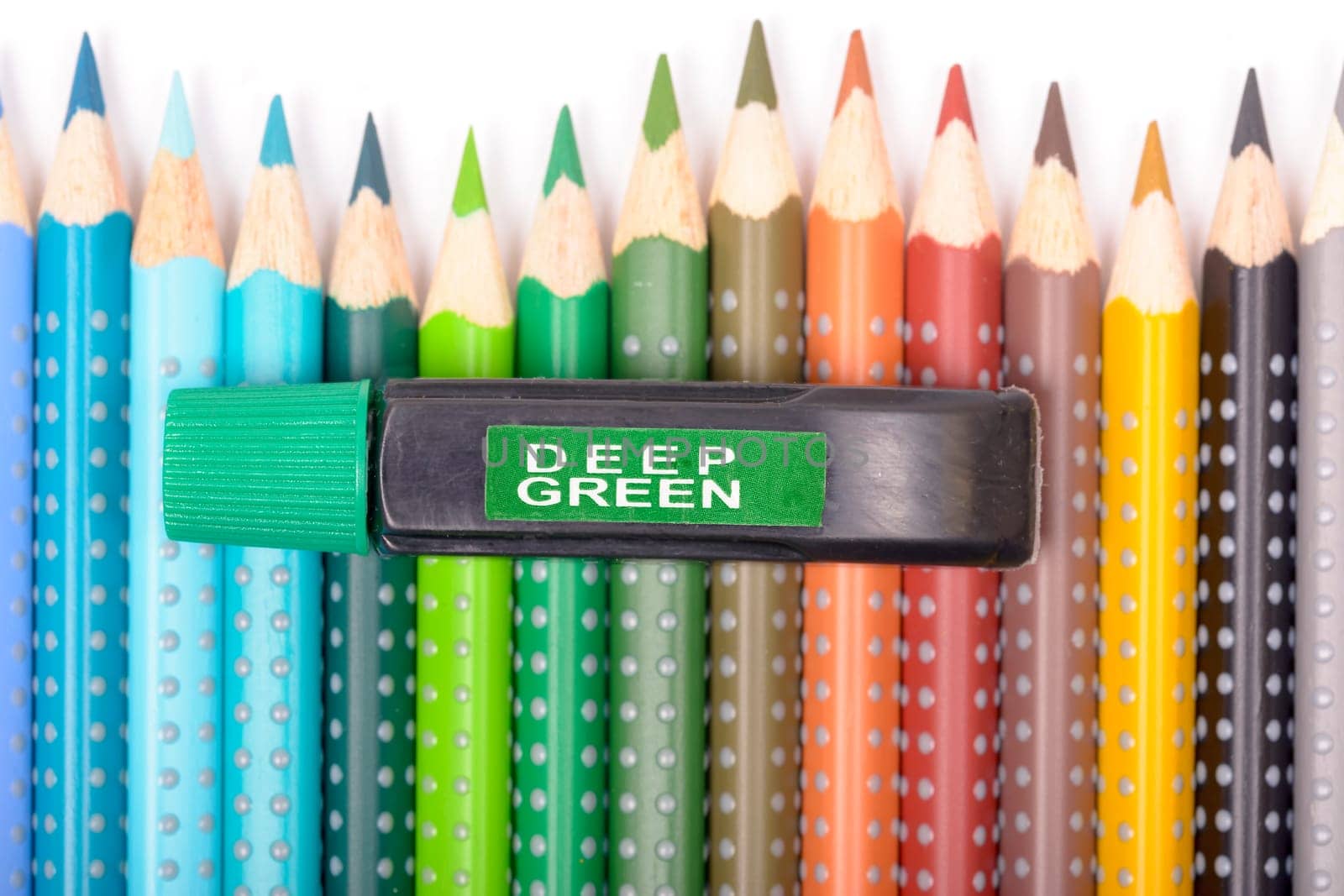 Bundle of colored pencils and tubes of paint on the colorful background