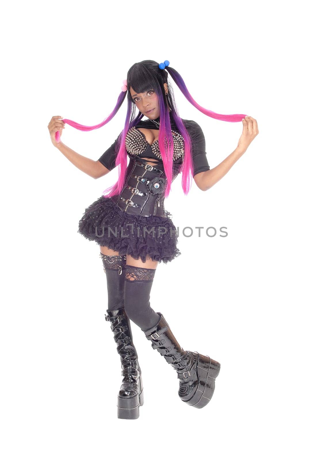 A beautiful African American steam punk woman in a corset and spike .bra standing in short skirt and long boots, isolated for white background..