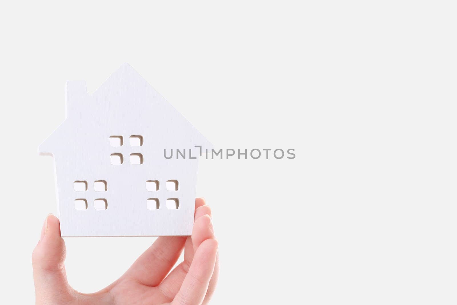 Hand holding miniature model of house on white background