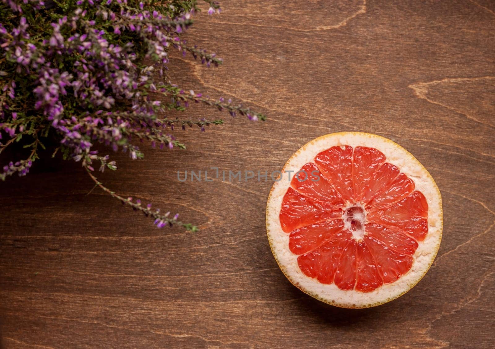 one cut red grapefruit on wooden brown background
