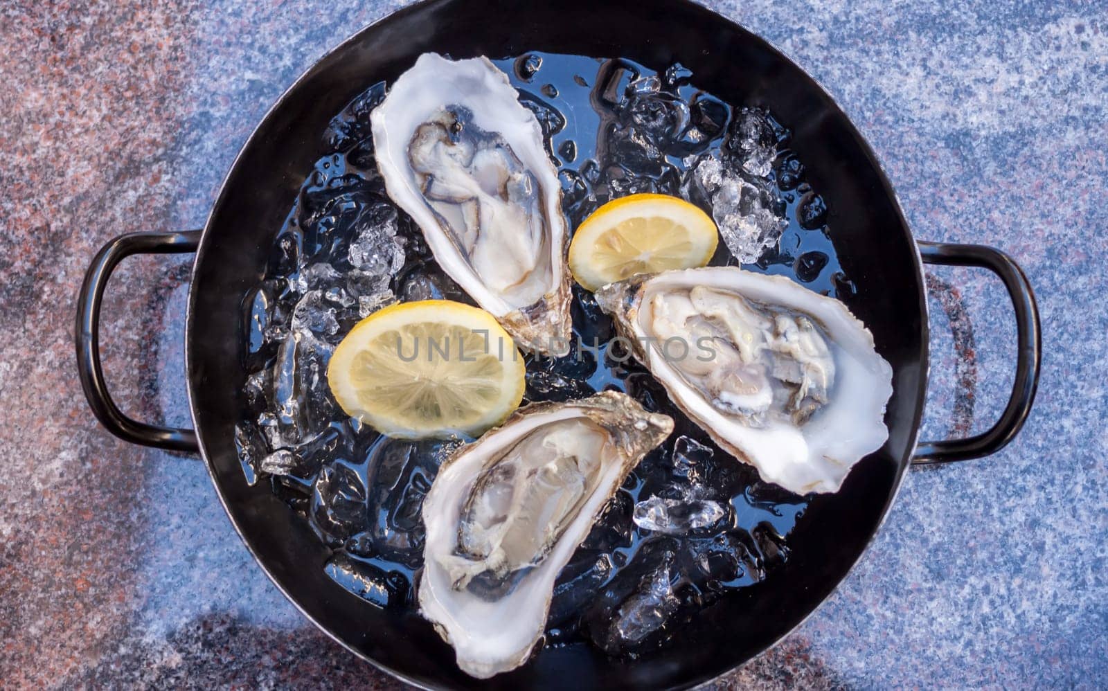 fresh opened oysters on metal black plate marble background