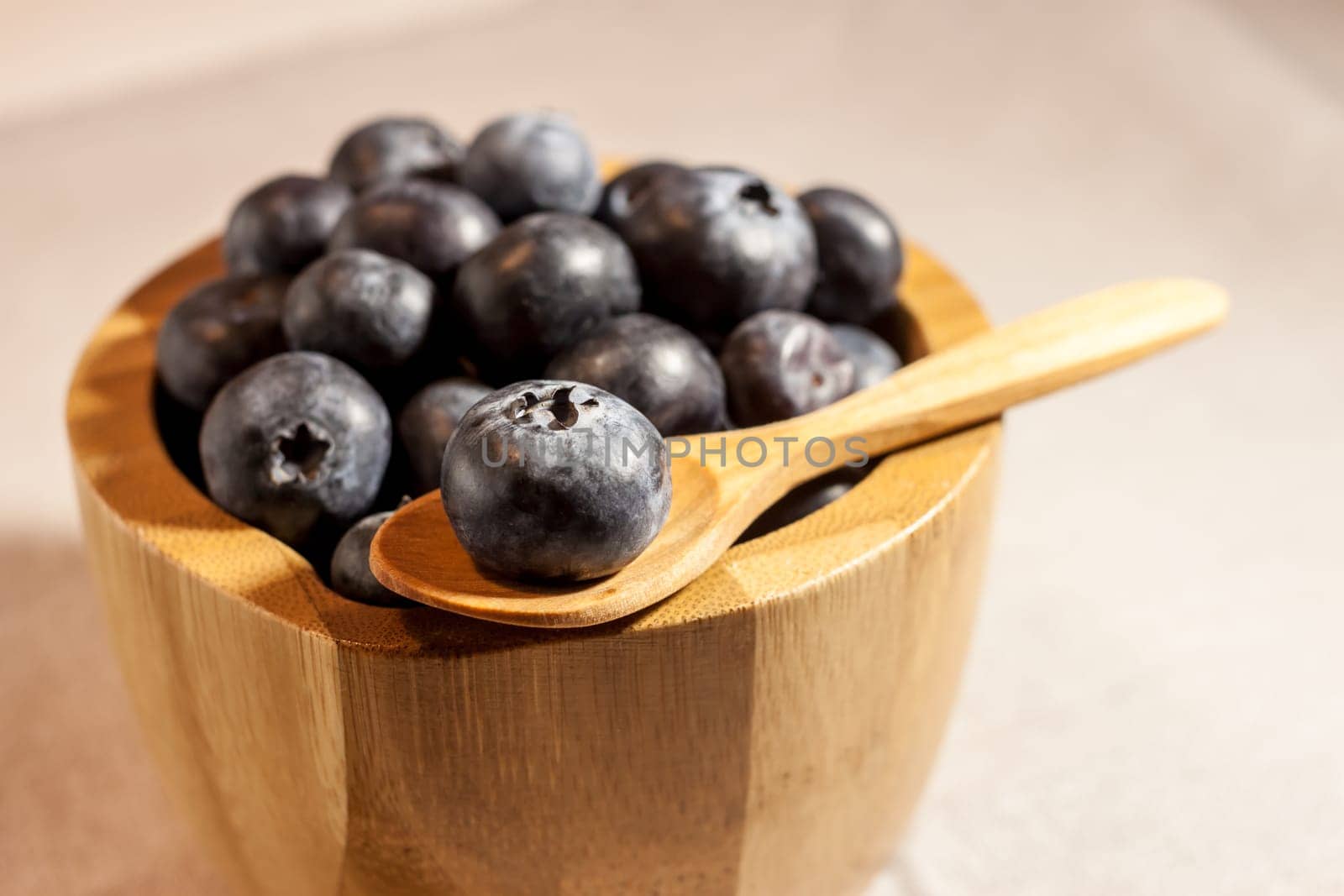 big blueberry in small wooden bowl on textile background