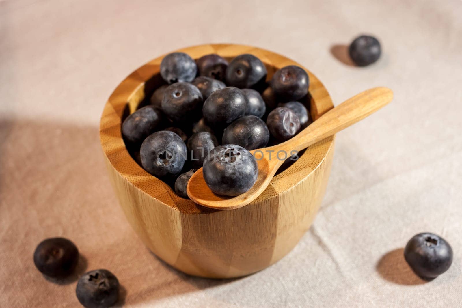 big blueberry in small wooden bowl on textile background