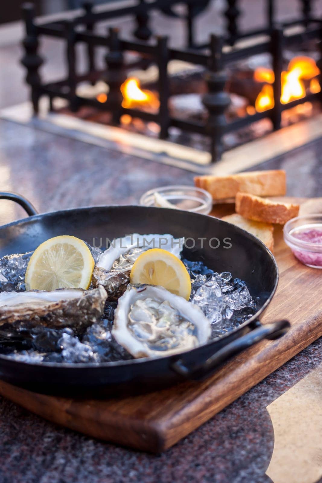 fresh opened oysters on metal black plate fireplace atbackground