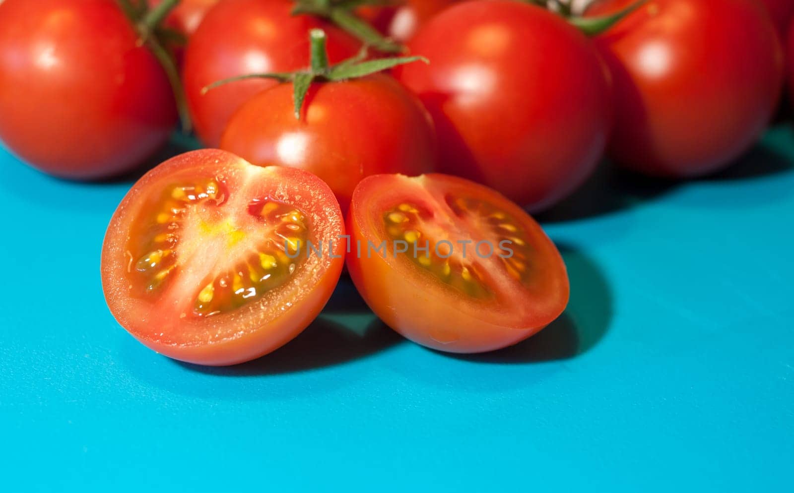 fresh ripe cherry tomatoes on blue background free space