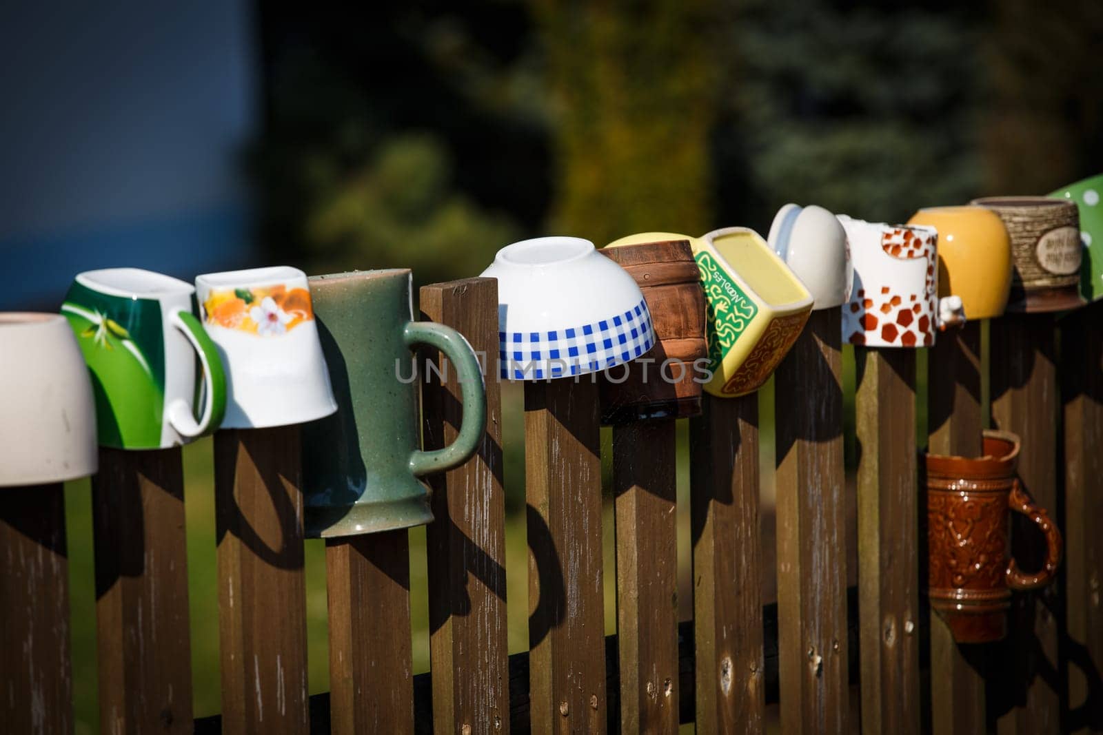 Mugs and pots hanging on the wooden fence