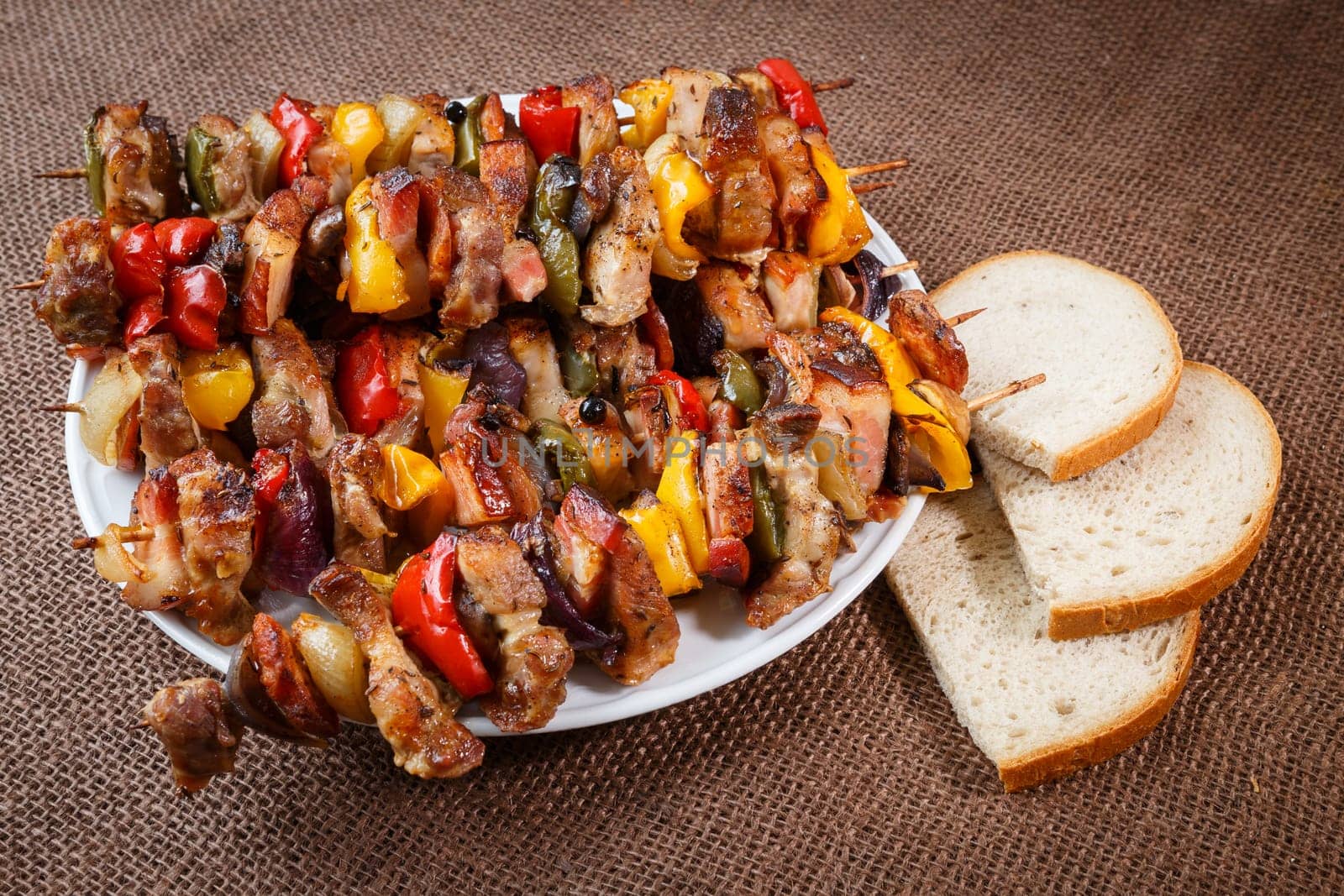Grilled meat skewers with vegetables and bread