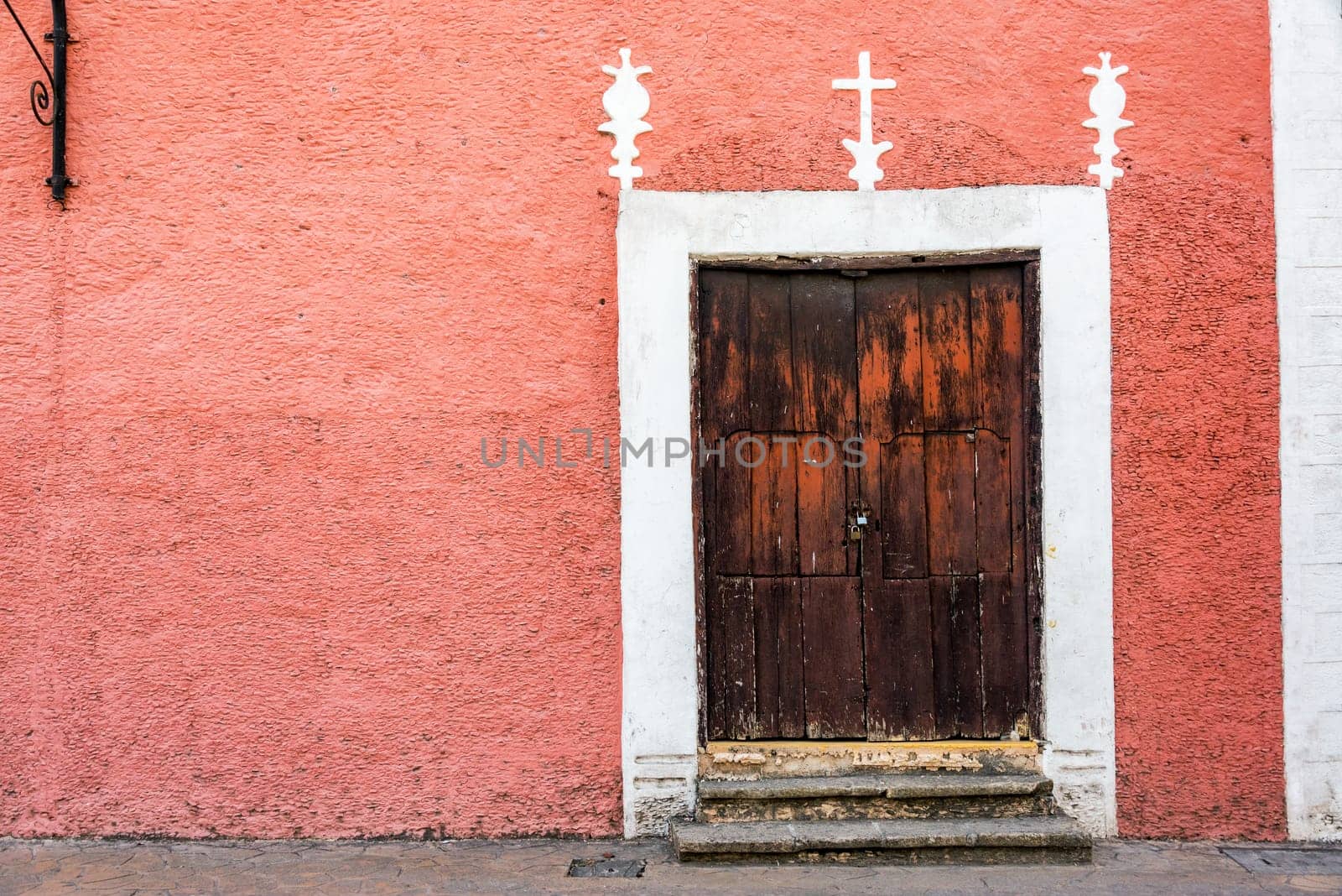 Pink colonial building and rustic wooden door in Valladolid, Mexico