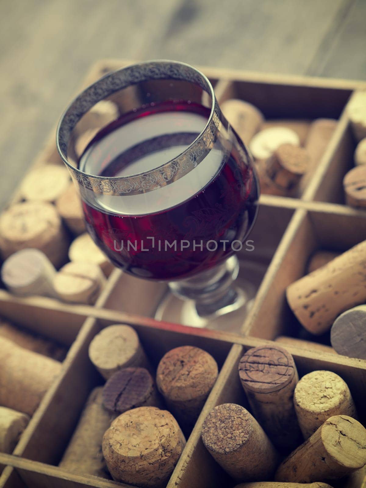 Close up of a glass of red wine with bottle corks, selective focus on the glass