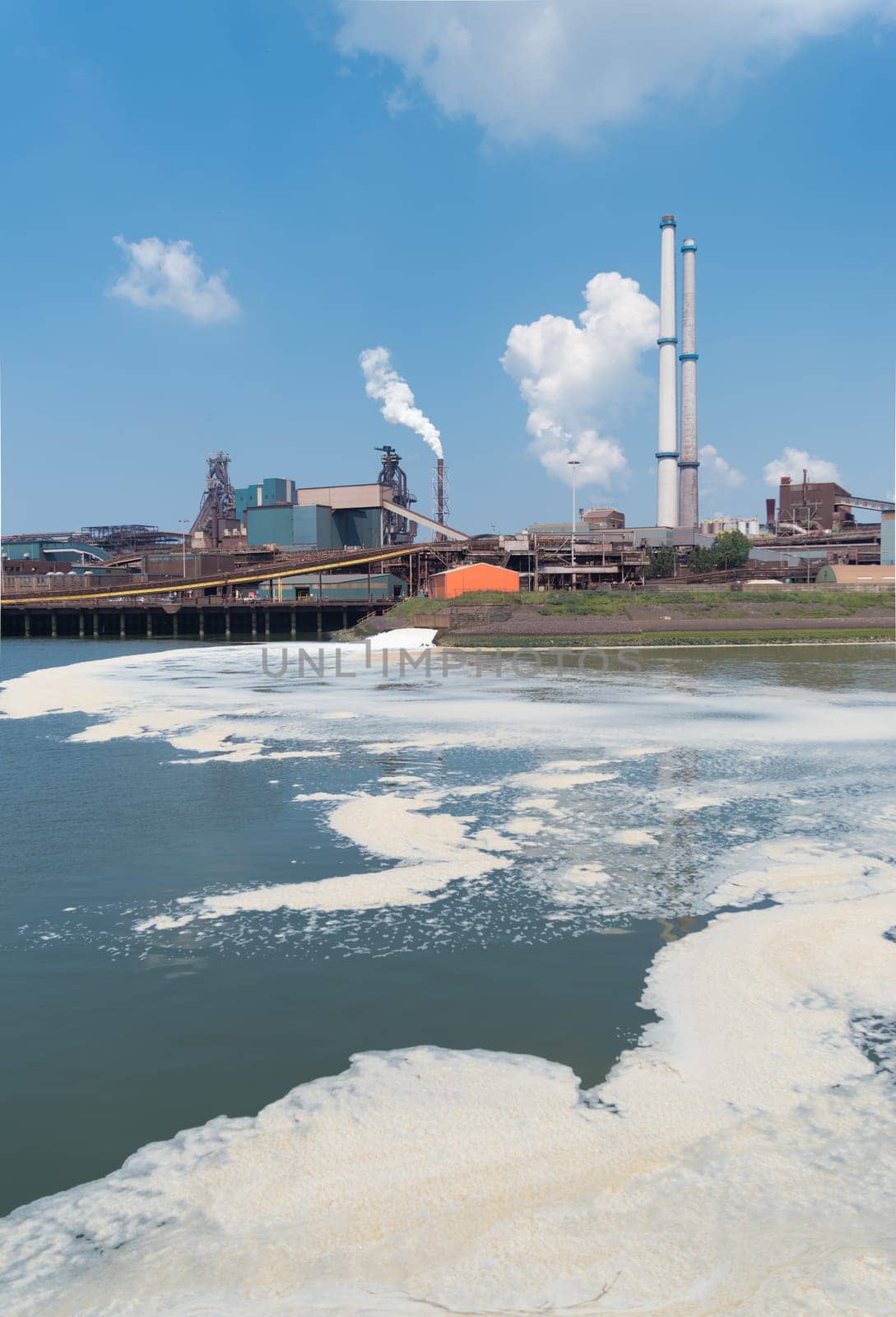 polluted water with a large steel plant in the background