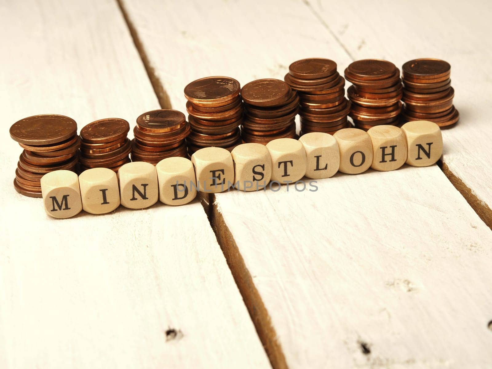 Minimum wage concept with wooden cubes and change as a pile of money