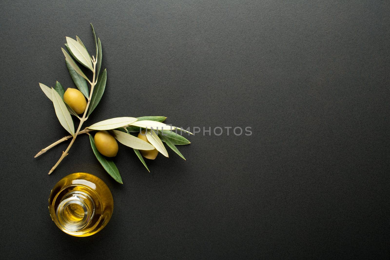 Olive oil and olive branch on black background
