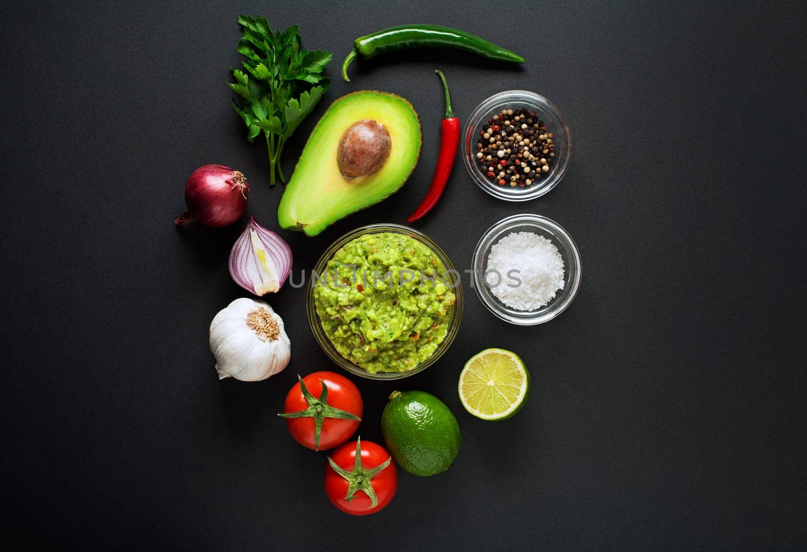 Avocado guacamole with fresh ingredients on black table