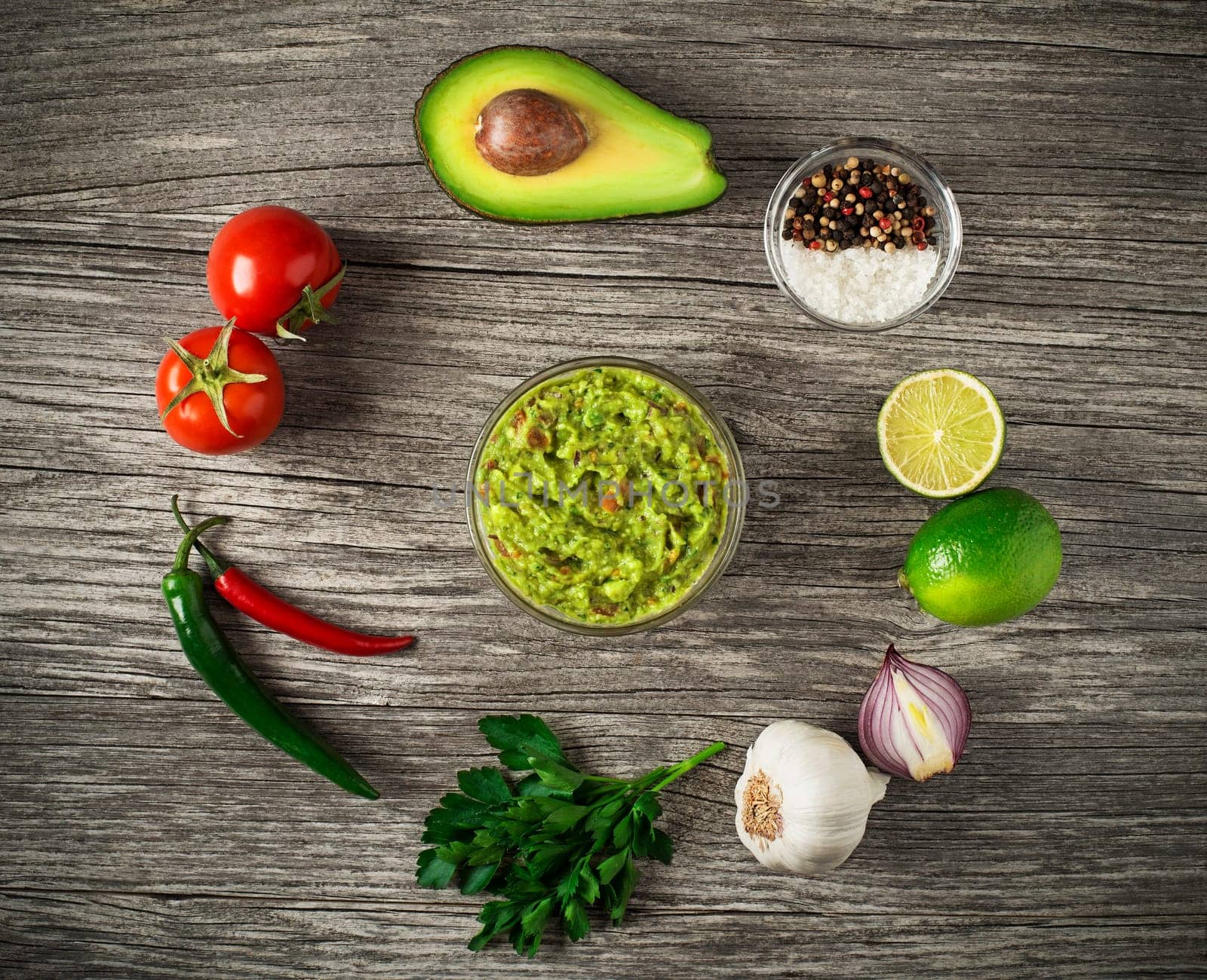 Avocado guacamole with fresh ingredients on wooden table