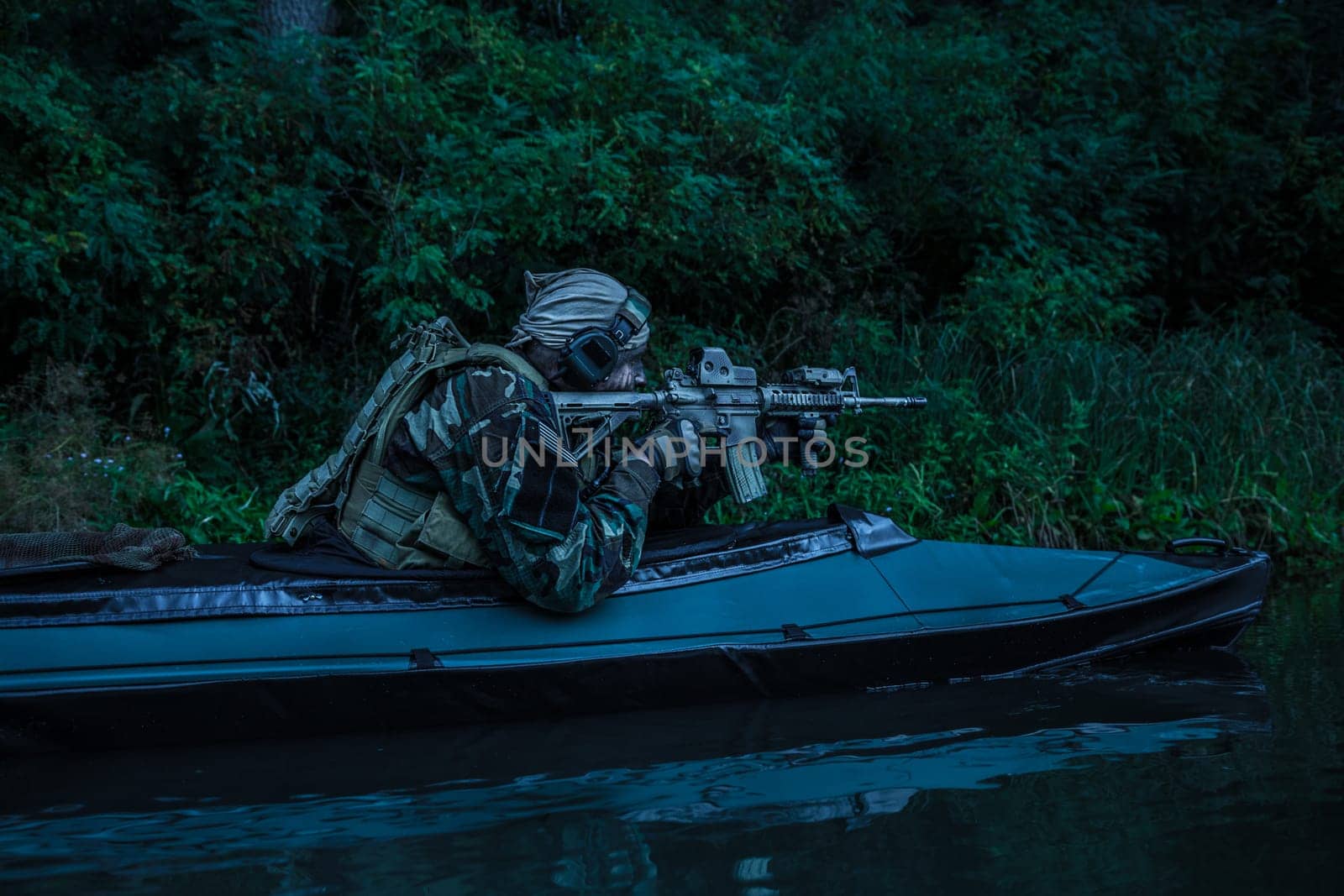 Special forces man with painted face in camouflage uniforms in army kayak. Seeking target, diversionary mission, twilight