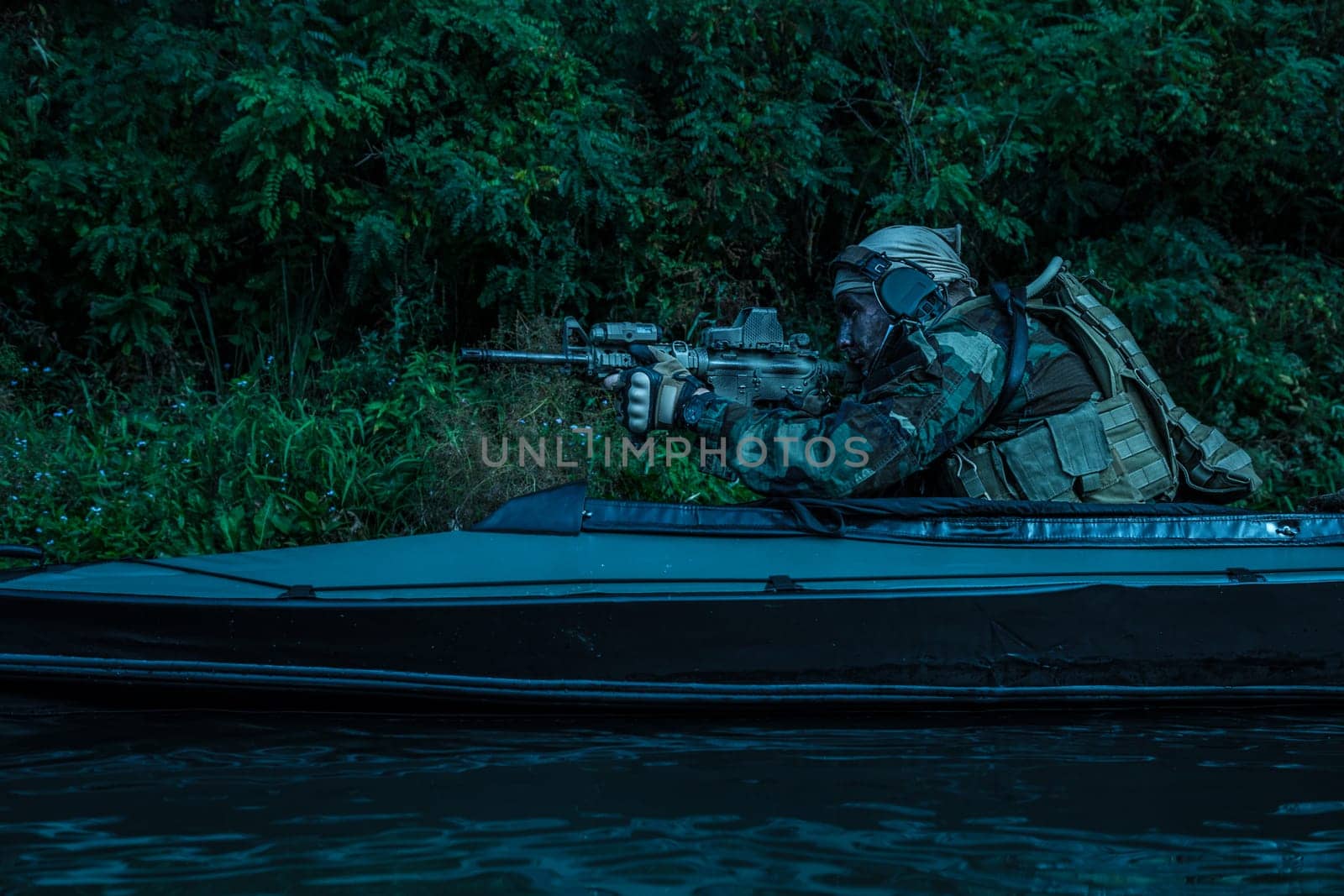 Special forces man with painted face in camouflage uniforms in army kayak. Seeking target, diversionary mission, twilight