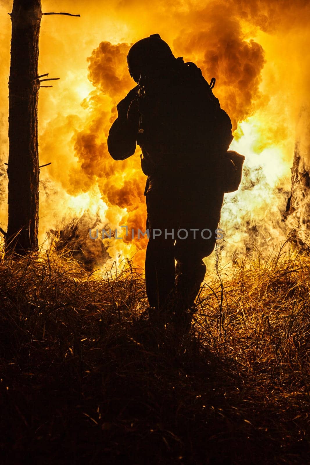 Backlit silhouette of special forces marine operator in forest on fire explosion background. Battle, bombs exploding, fighting no matter what
