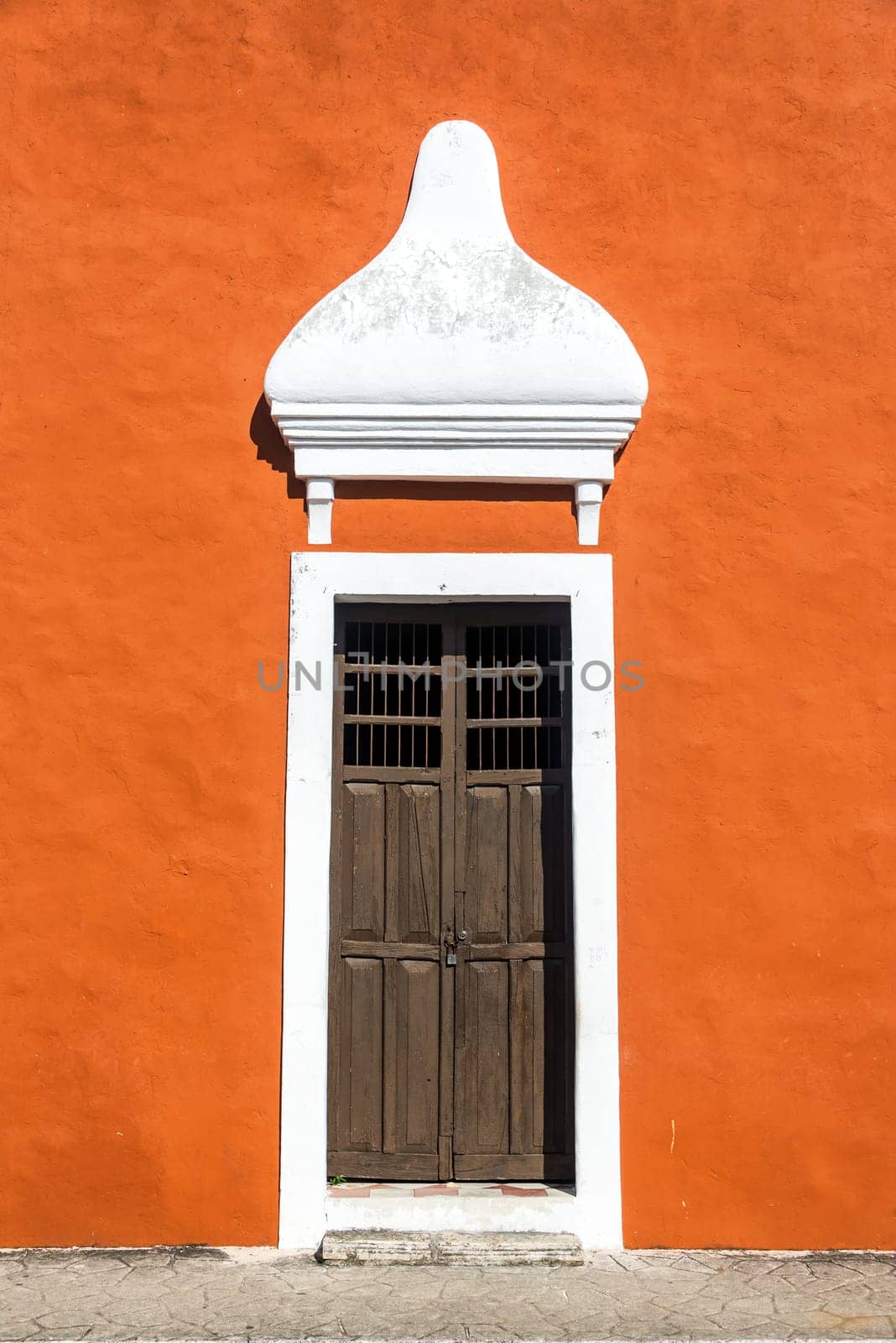 Old wooden door on an orange colonial building in the historic center of Valladolid, Mexico