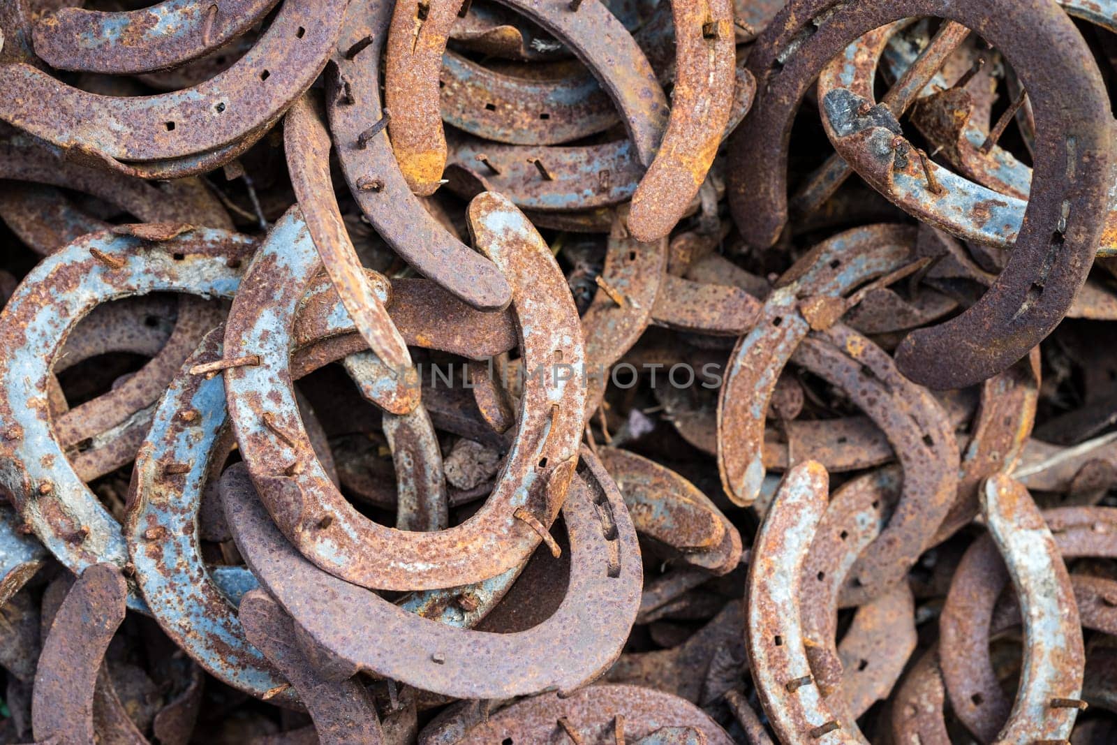 Heap of used and worn rusty Horseshoes outside blacksmith farriers shop or smithy