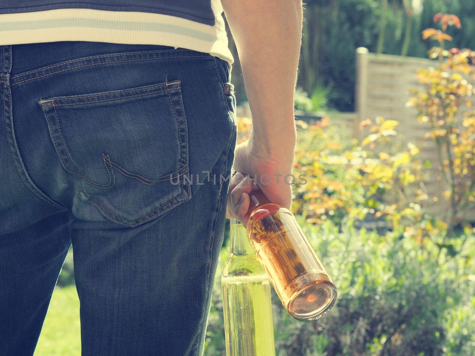 Young man with two bottles of apple juice in the garden